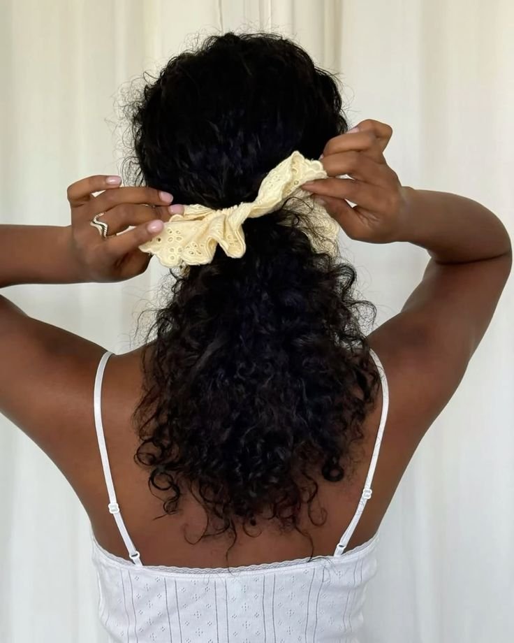 Cabelo cacheado preso suavemente com uma fita amarela, criando um penteado sem tração.