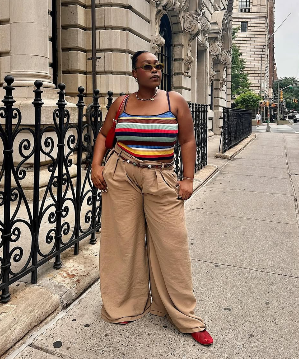 Pessoa com regata listrada e calça bege em rua urbana; usa sapatilhas estilosas vermelhas.