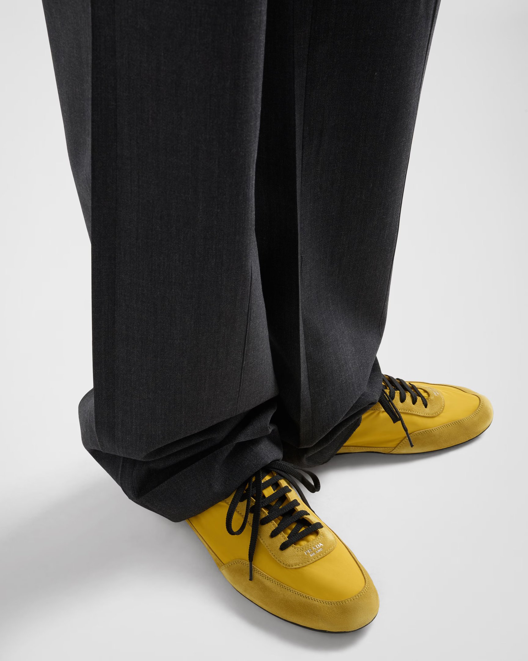 Calças escuras combinadas com sapatos do momento amarelos vibrantes e cadarços pretos.