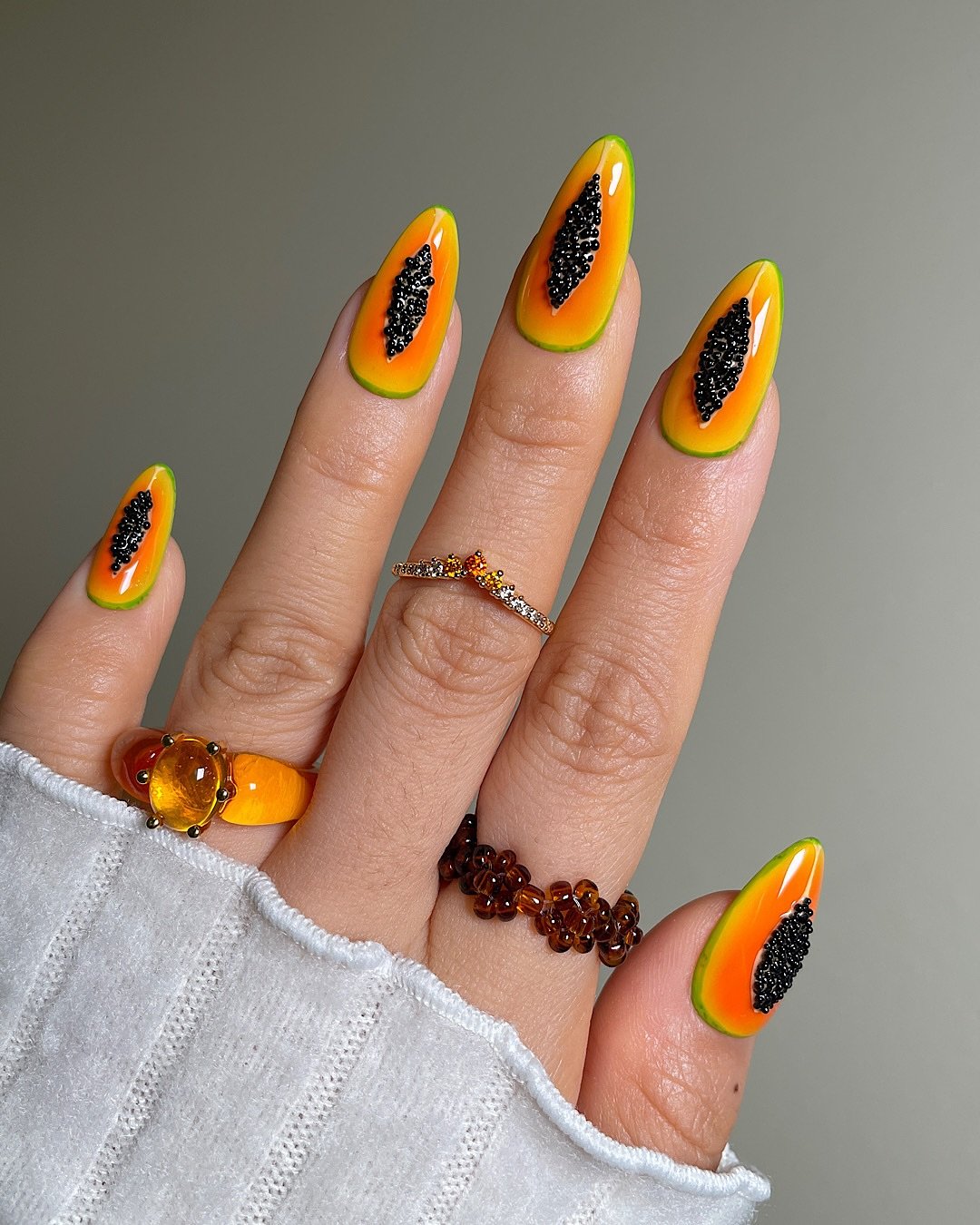 Unhas coloridas com detalhes preto e desenho de papaya, tendência para summer nails 2025.
