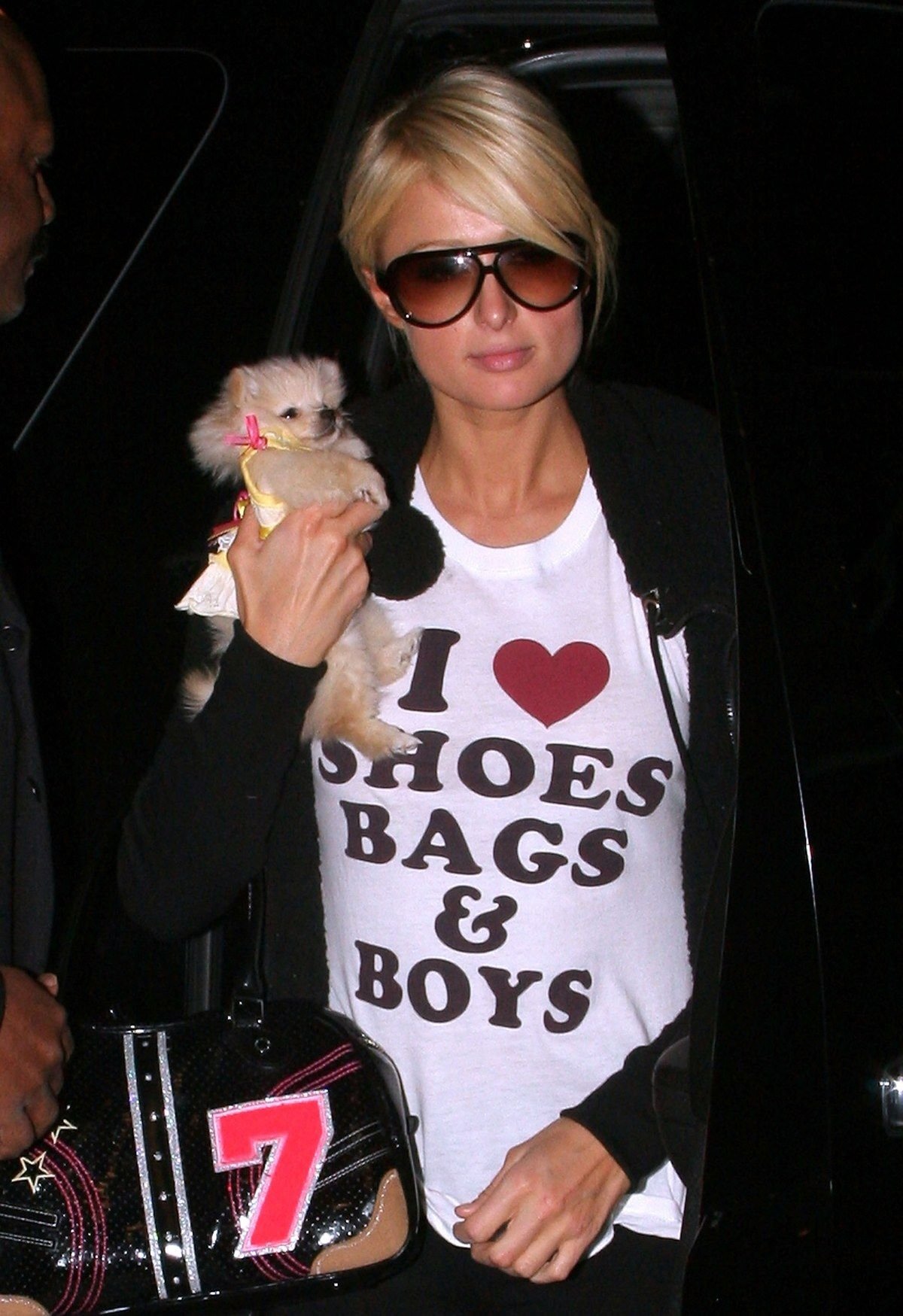 Pessoa segurando um pequeno cachorro, usando camiseta com a frase 