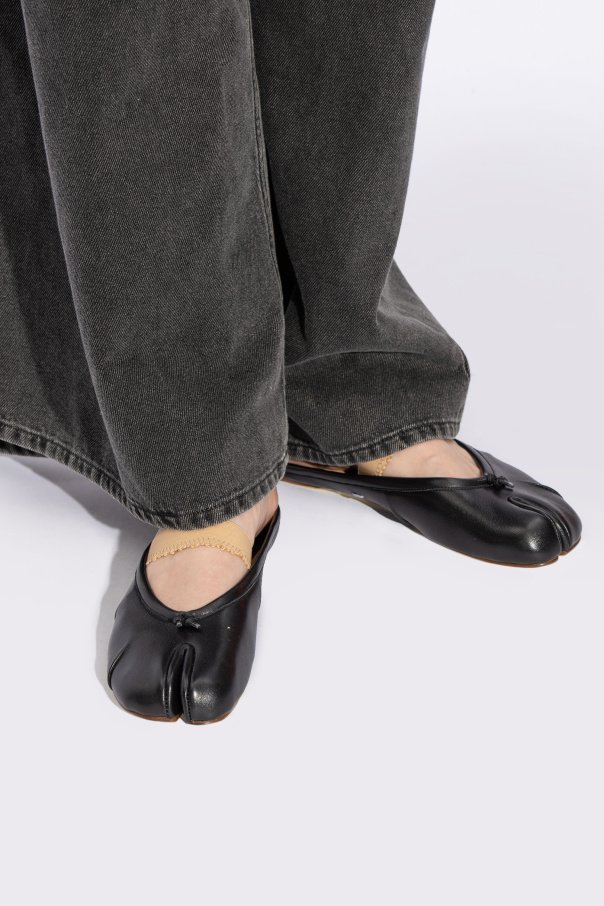 Na imagem, pés calçados com sapatos pretos de bico fendido. sandálias Kolhapuri
