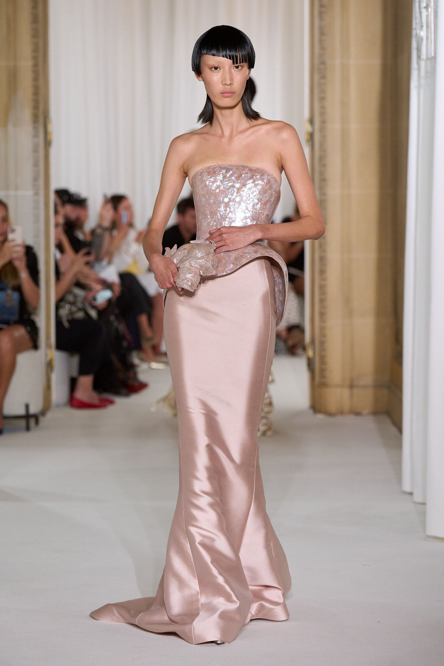 Modelo desfila com vestido elegante em rosa cintilante, refletindo tendências da alta-costura.