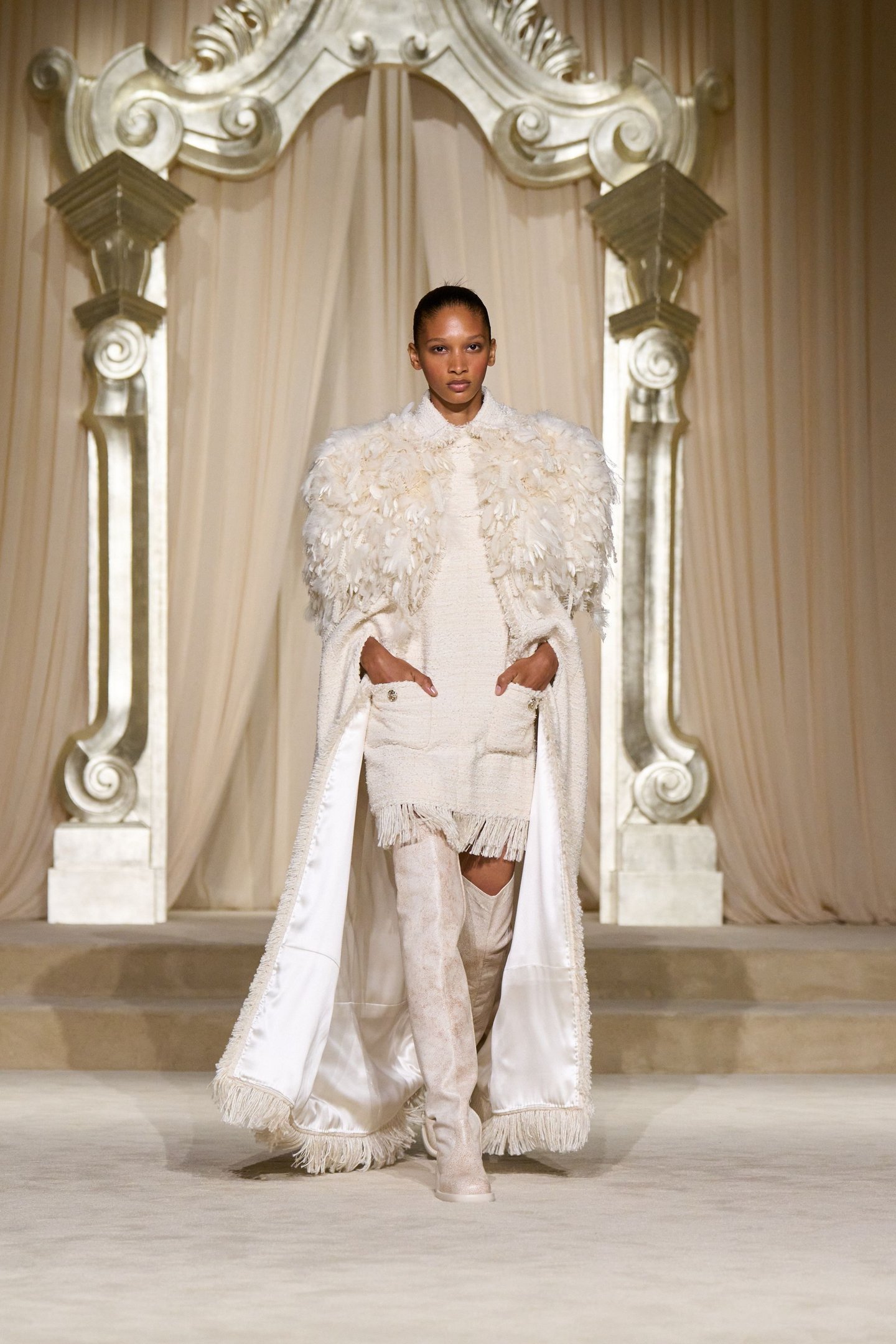 Desfile de moda apresenta modelo em terno cinza e gravata de bolinhas, refletindo tendências da alta-costura.