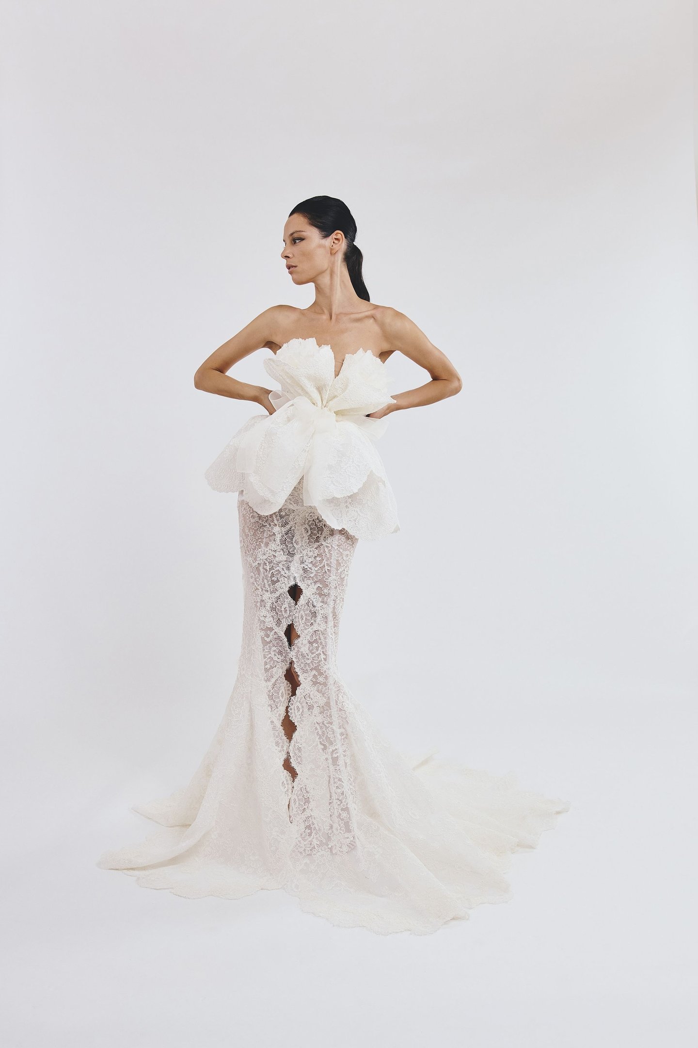 Modelo em vestido de renda sofisticado com laço impactante, refletindo tendências da semana de alta-costura.