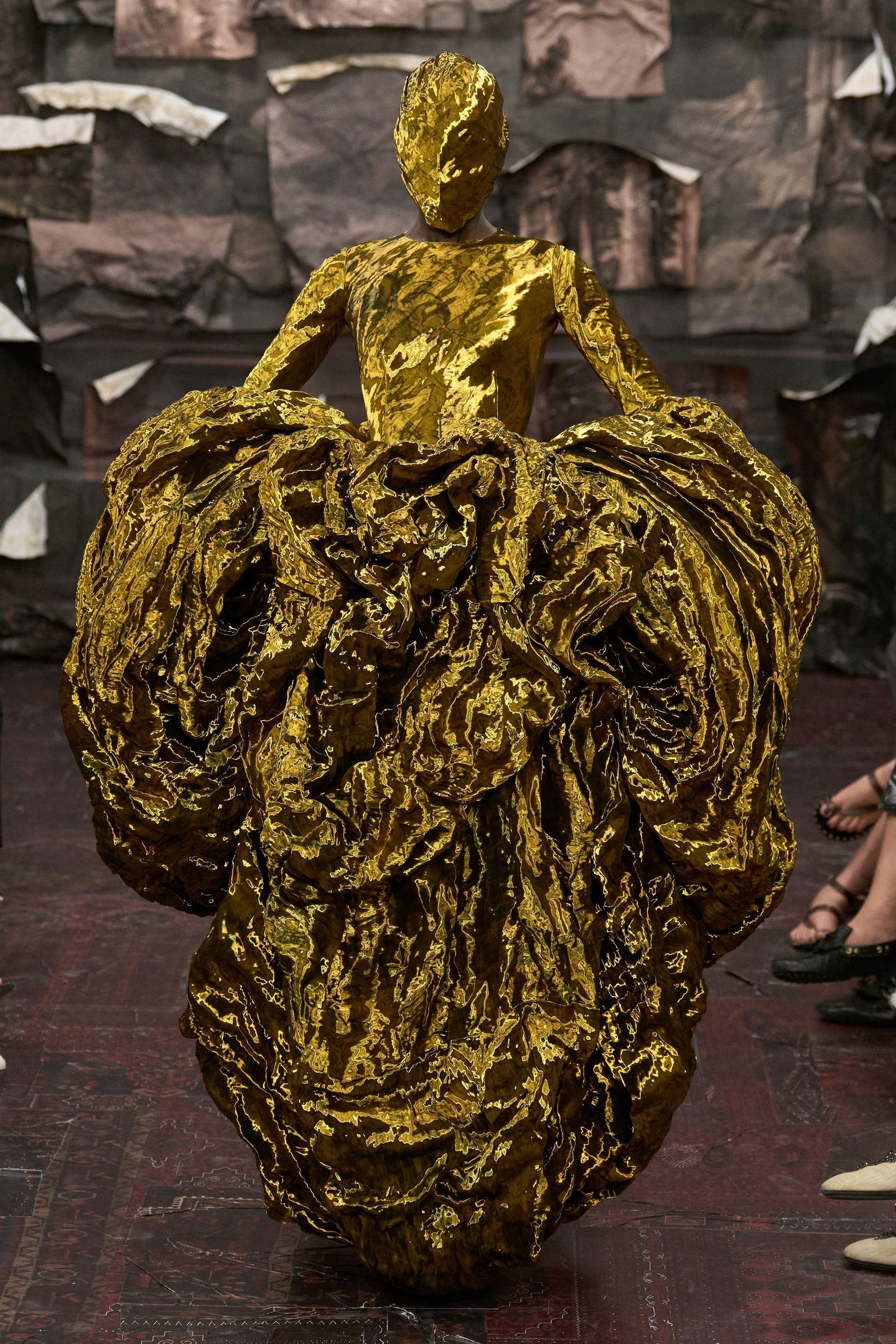 Modelo em desfile vestindo traje dourado texturizado, refletindo tendências da alta-costura.