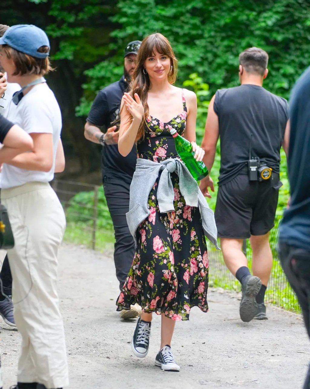 Pessoas andando ao ar livre, mulher sorrindo com tênis estilosos e vestido floral.
