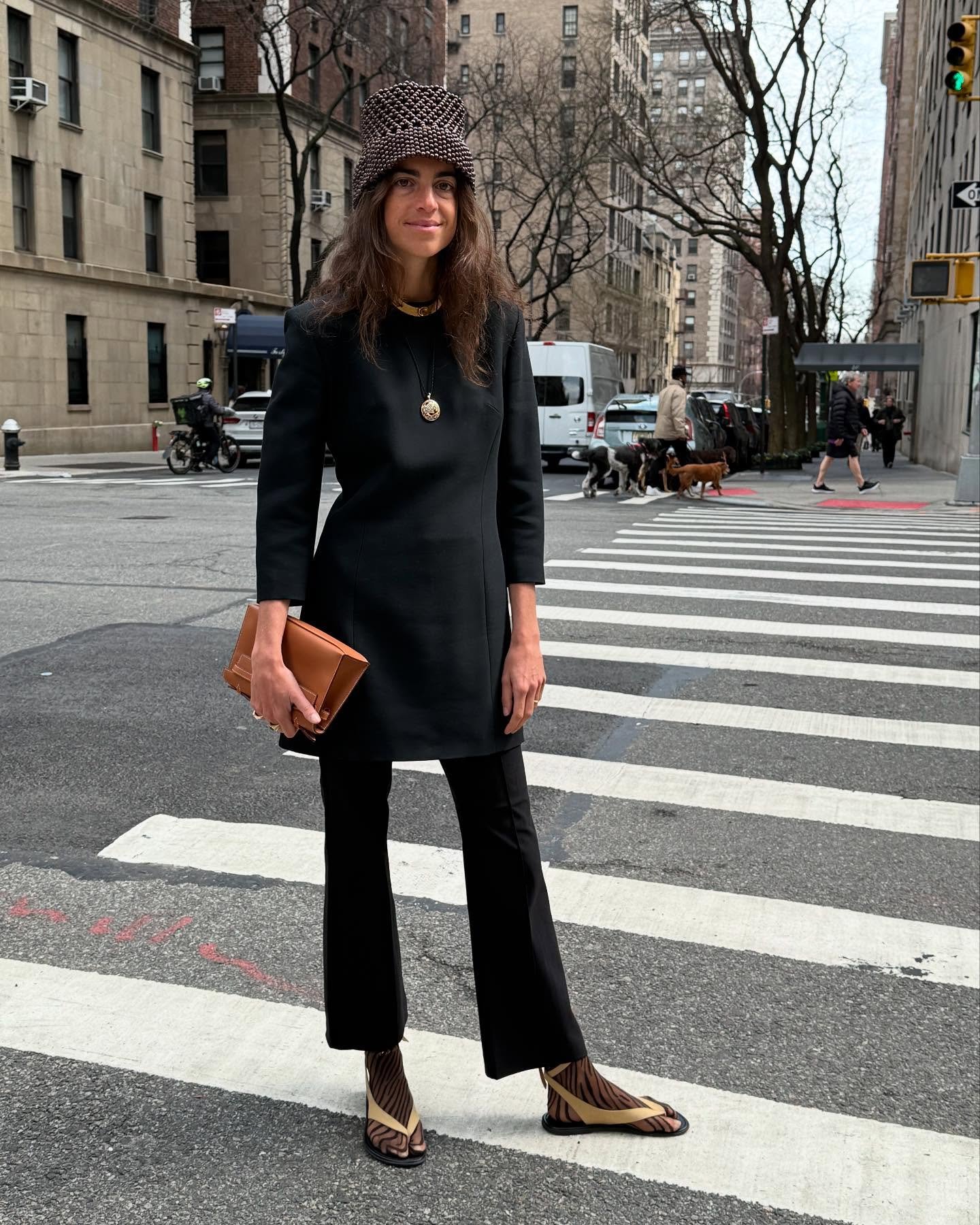 Pessoa com chapéu de crochê e sapatos inusitados no estilo teoria do sapato errado, em cidade com prédios.