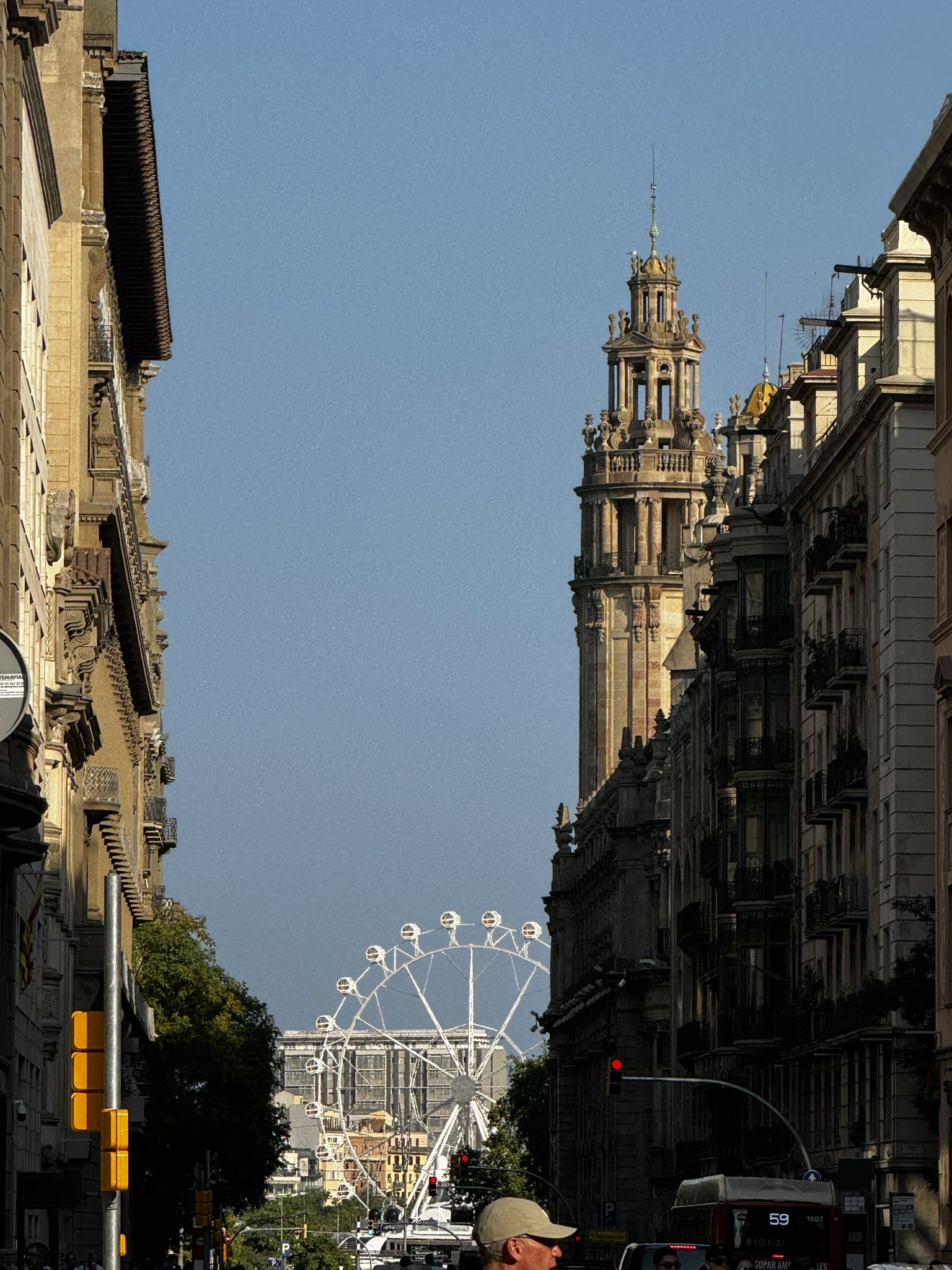 Rua movimentada com roda-gigante ao fundo e céu claro, capturando o clima do verão europeu.