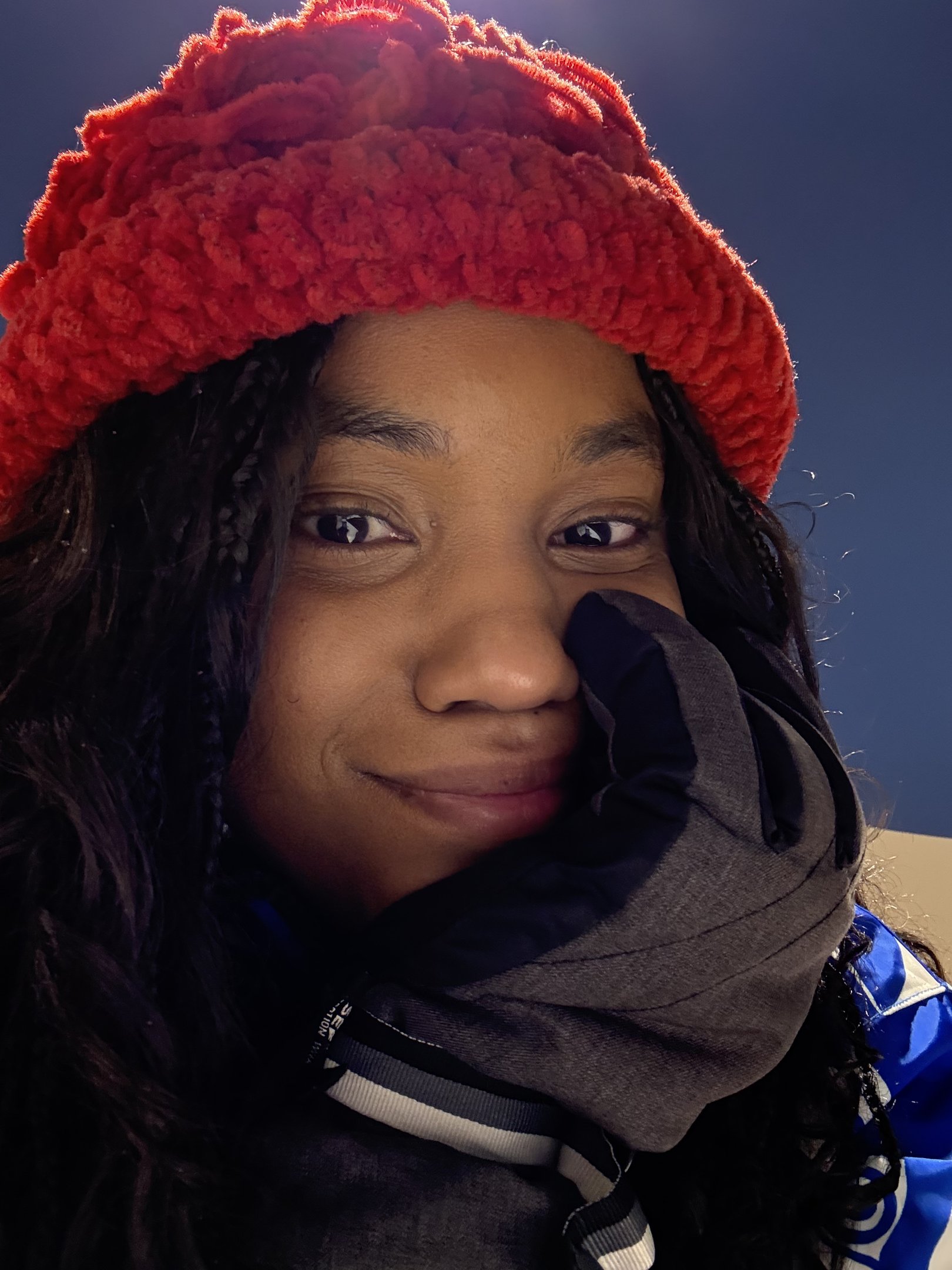Pessoa sorrindo com gorro vermelho e luva, sugerindo um momento especial durante uma viagem internacional.