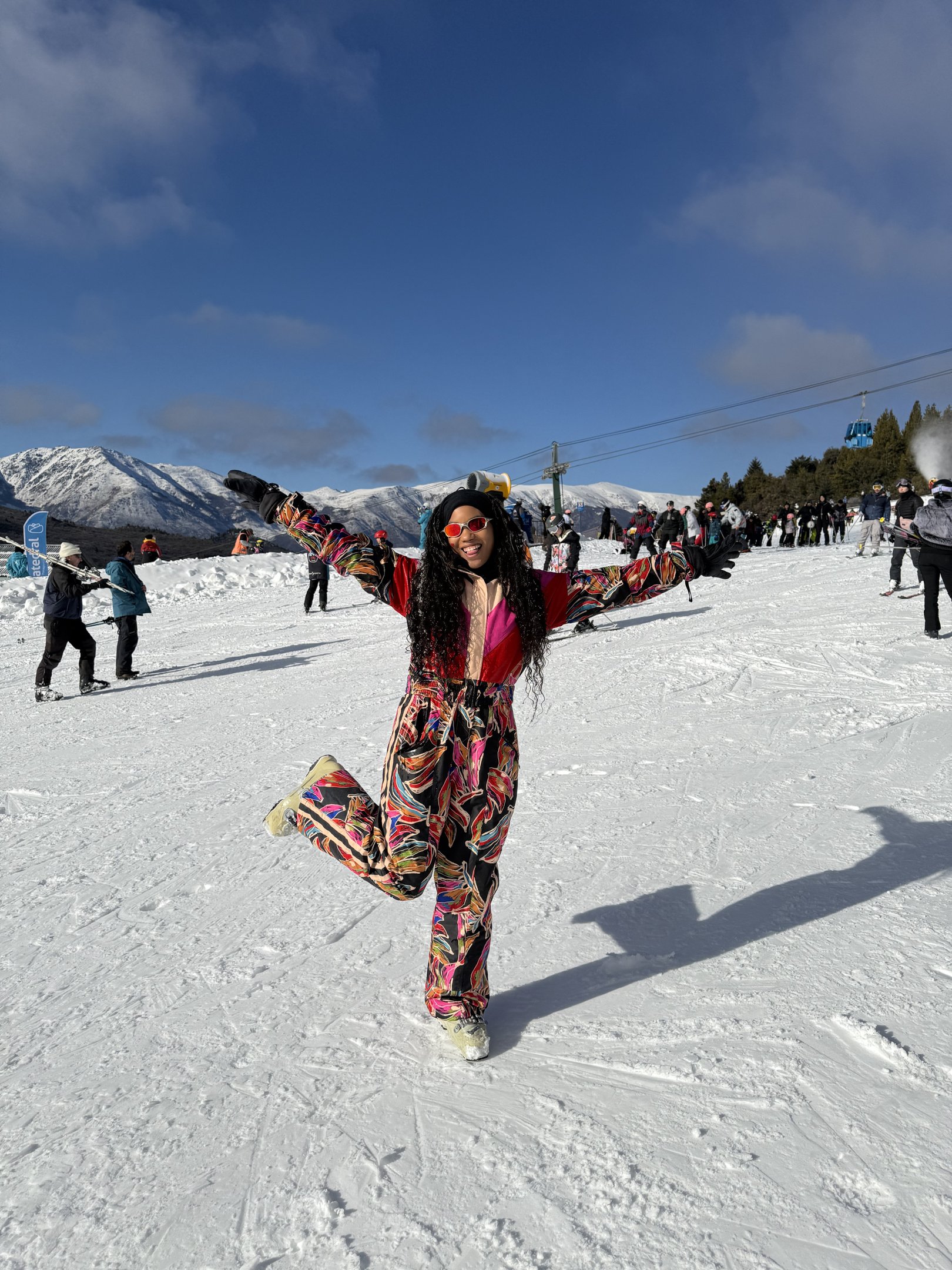 Esquiadora sorridente desfruta de uma viagem internacional na neve, rodeada por montanhas.