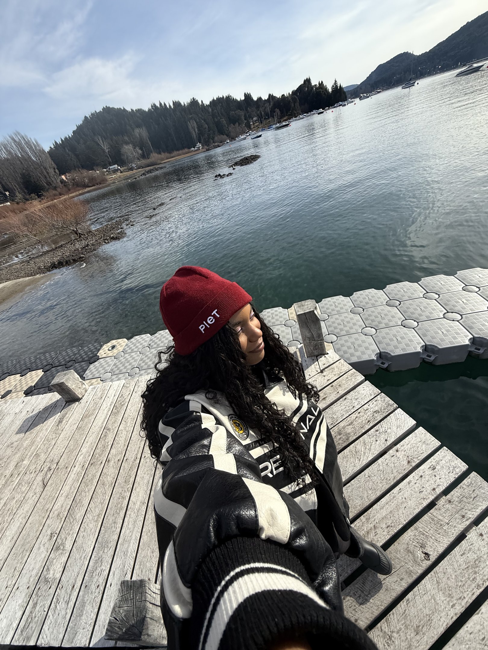Jovem em um píer à beira de um lago sereno, cenário ideal para uma viagem internacional relaxante.
