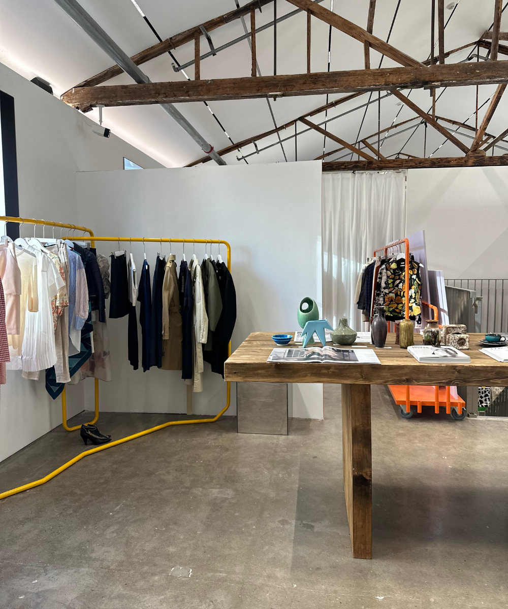 Loja com roupas em araras e objetos decorativos em mesa de madeira. Elementos de moda modernos.