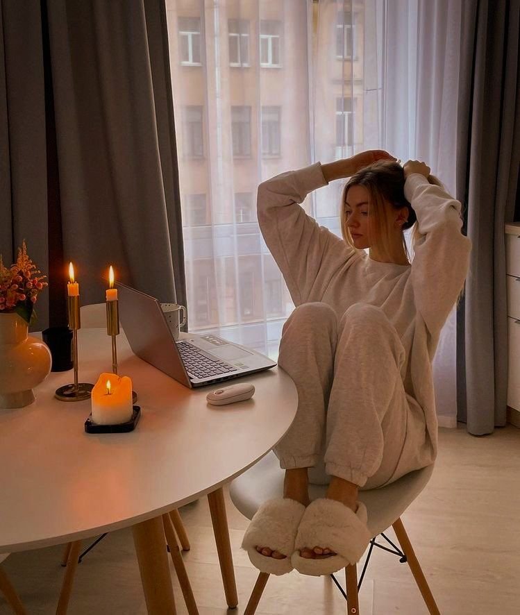 Sala aconchegante com laptop, velas acesas e pessoa relaxando na cadeira.tratamento contra disruptores endócrinos não é visível.