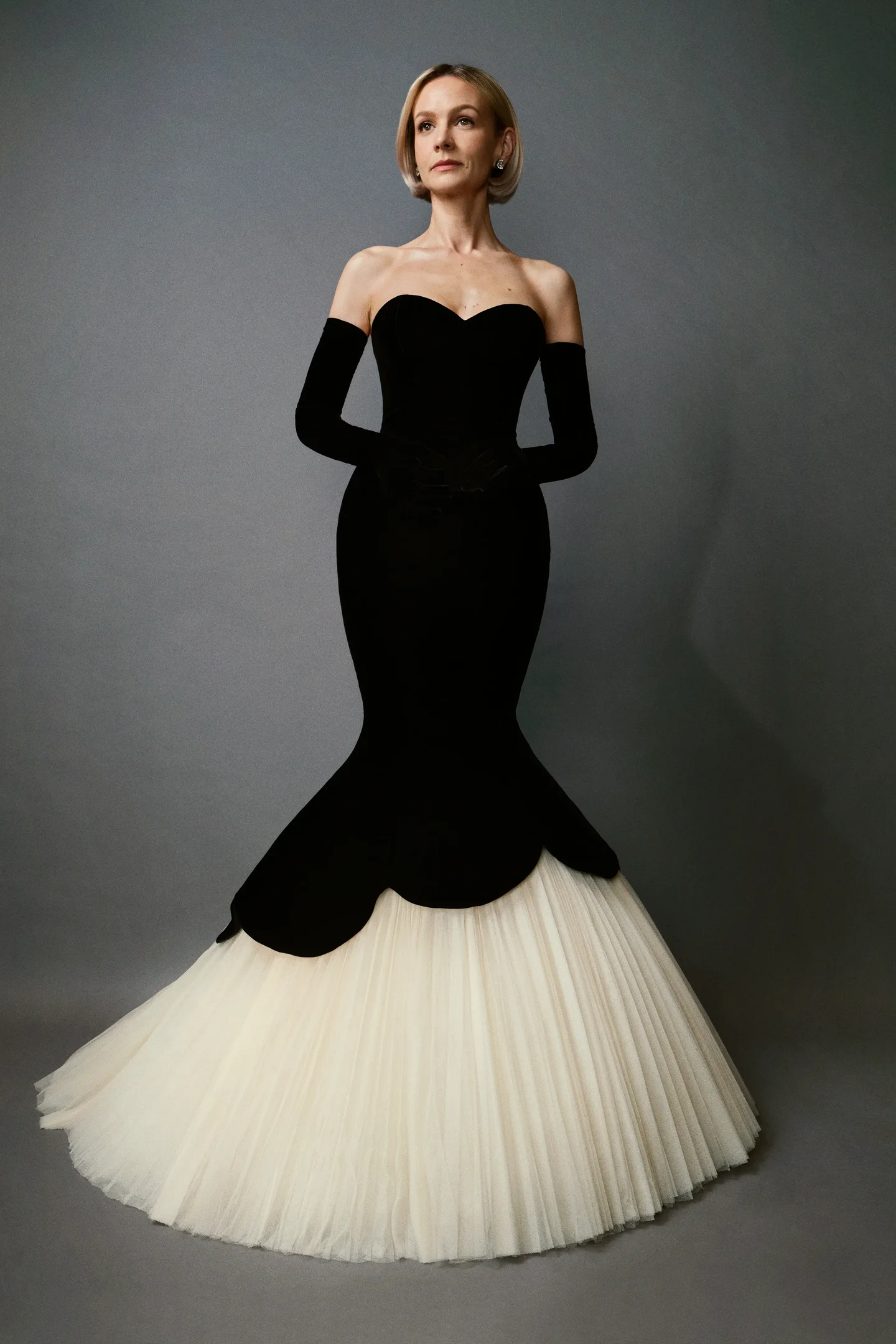 Andrew Mukamal veste Carey Mulligan com vestido preto e branco elegante, sem mangas e com cauda volumosa.