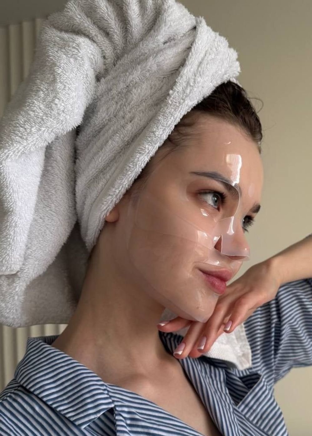 Pessoa com máscara facial transparente e toalha na cabeça.