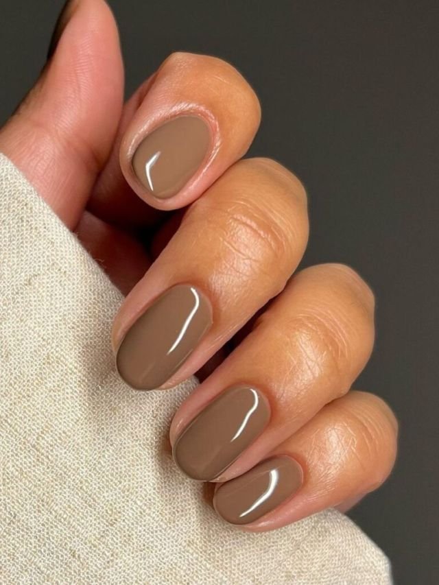 Unhas esmaltadas em tom marrom suave, tendência de cores de esmalte 2025.