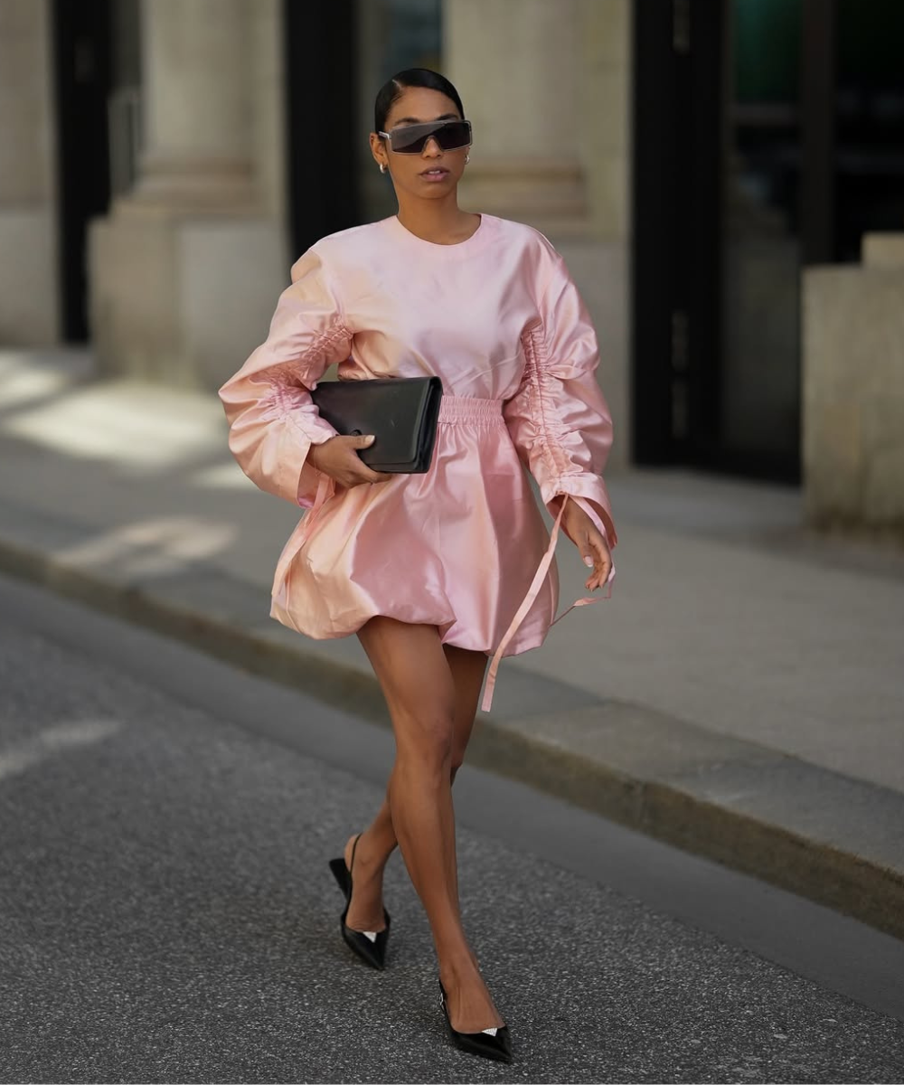 Vestido rosa brilhante e sapatos pretos usados em desfile urbano, seguindo tendências de cores do verão 2026.