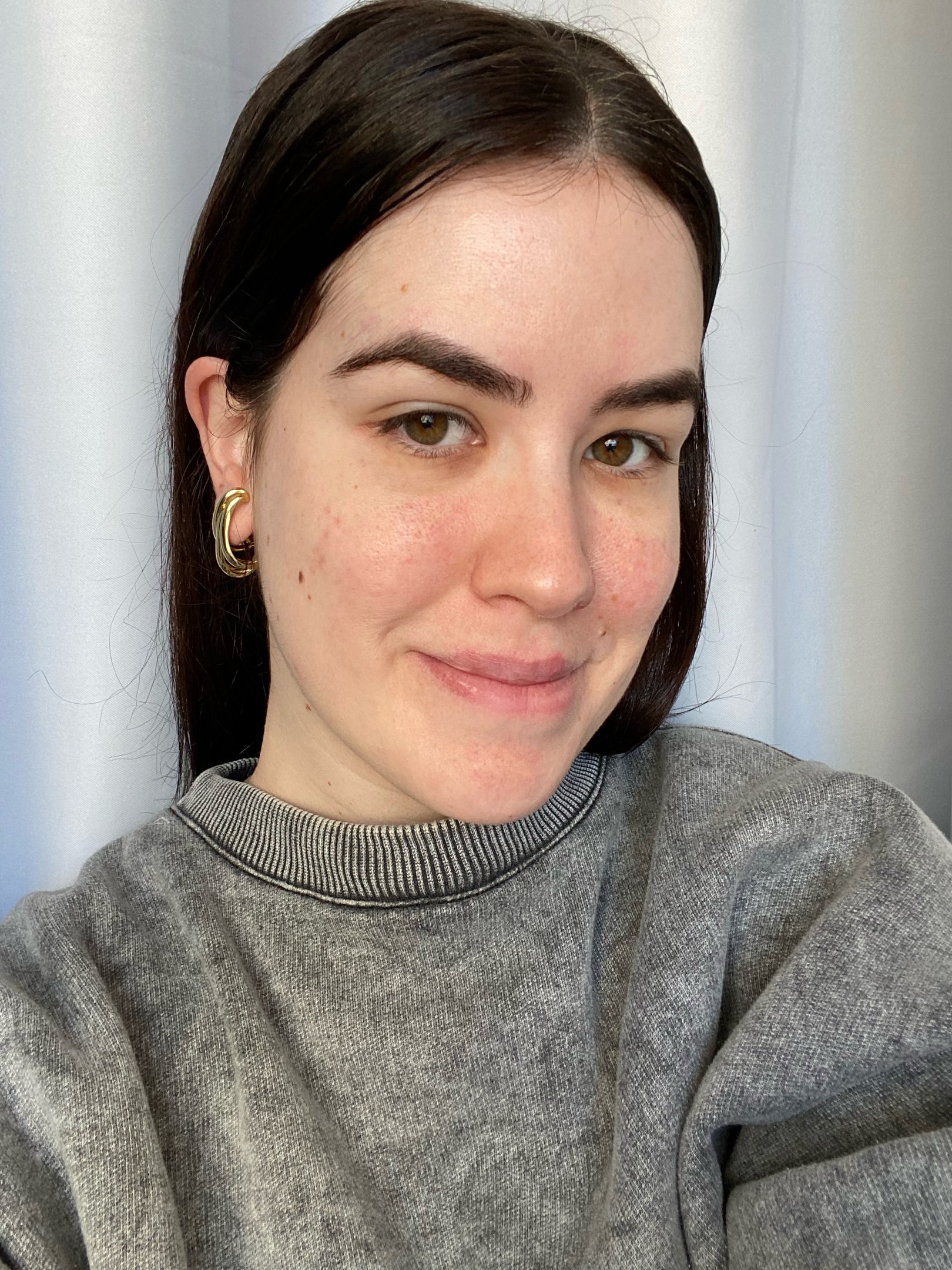 Pessoa sorrindo suavemente, usando jaqueta jeans, depois de 7 dias usando o sérum com retinol, Reviline da Mantecorp