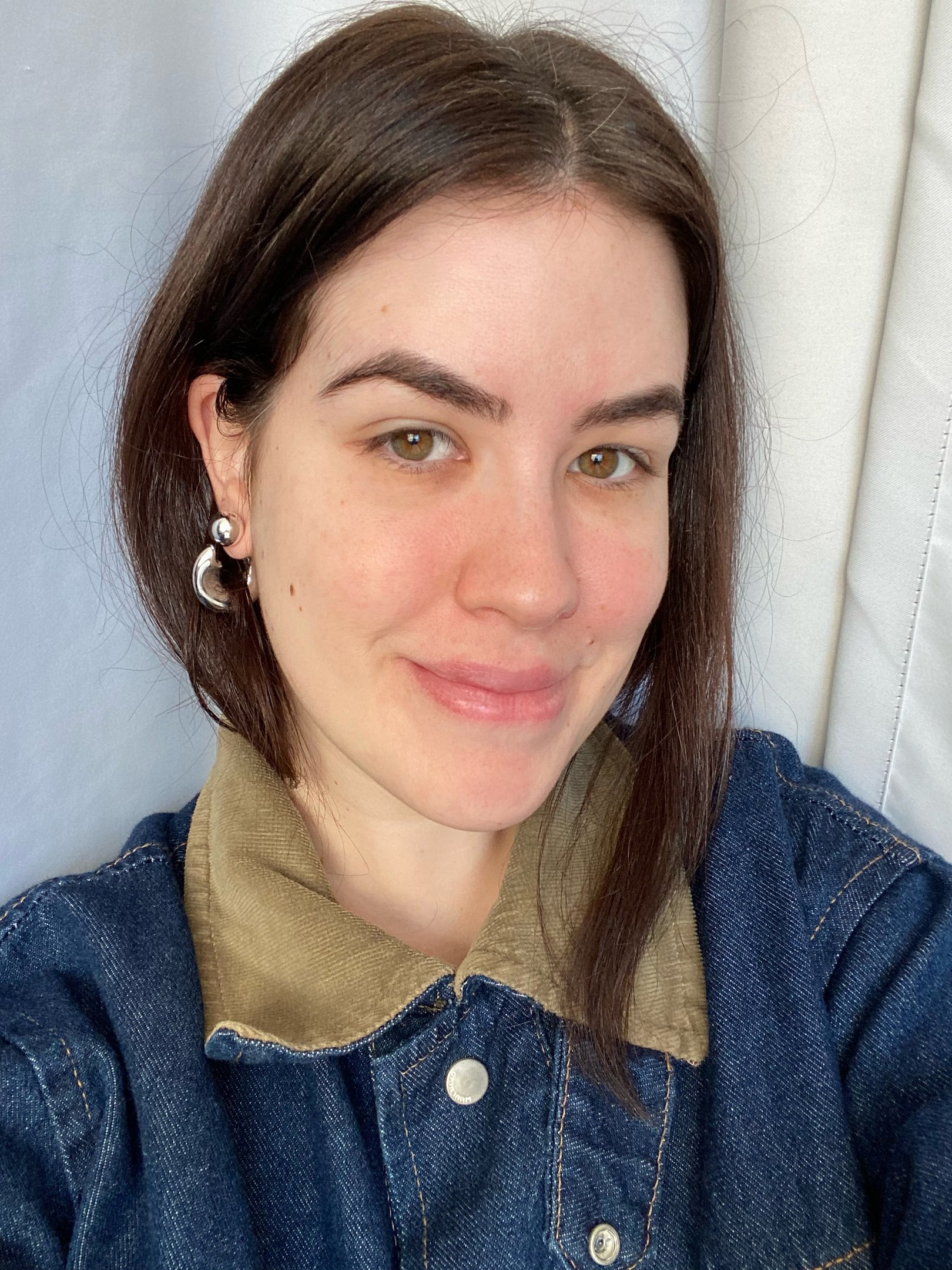 Pessoa sorrindo suavemente, usando jaqueta jeans, depois de 7 dias usando o sérum com retinol, Reviline da Mantecorp