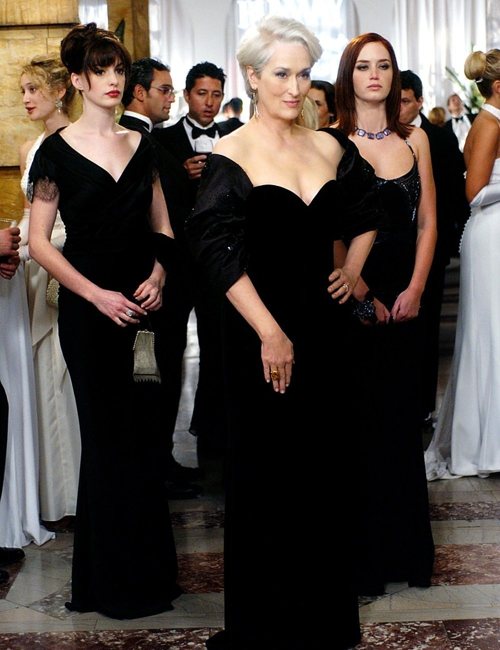 Três mulheres em vestidos de gala pretos, em um evento sofisticado, com expressões sérias. Molly Rogers não diretamente relacionada.