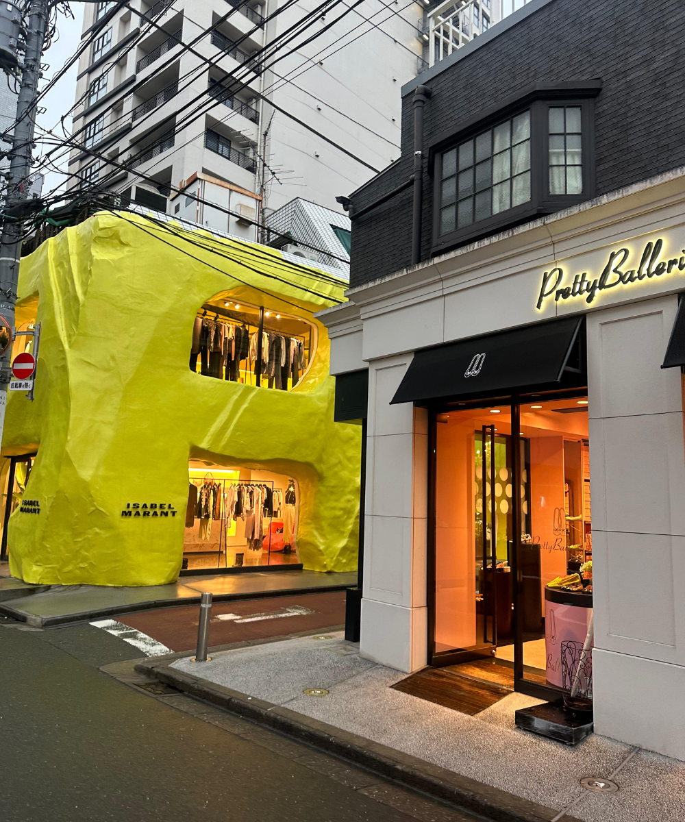 Fachada de lojas modernas e coloridas em rua urbana asiática, com edifícios altos ao fundo.