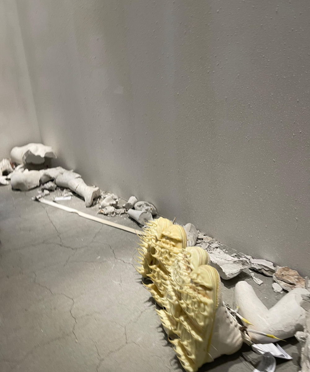 Entulho e escultura abstrata em espaço interno, evocando arte contemporânea. Superfície e formas irregulares de objetos associados.