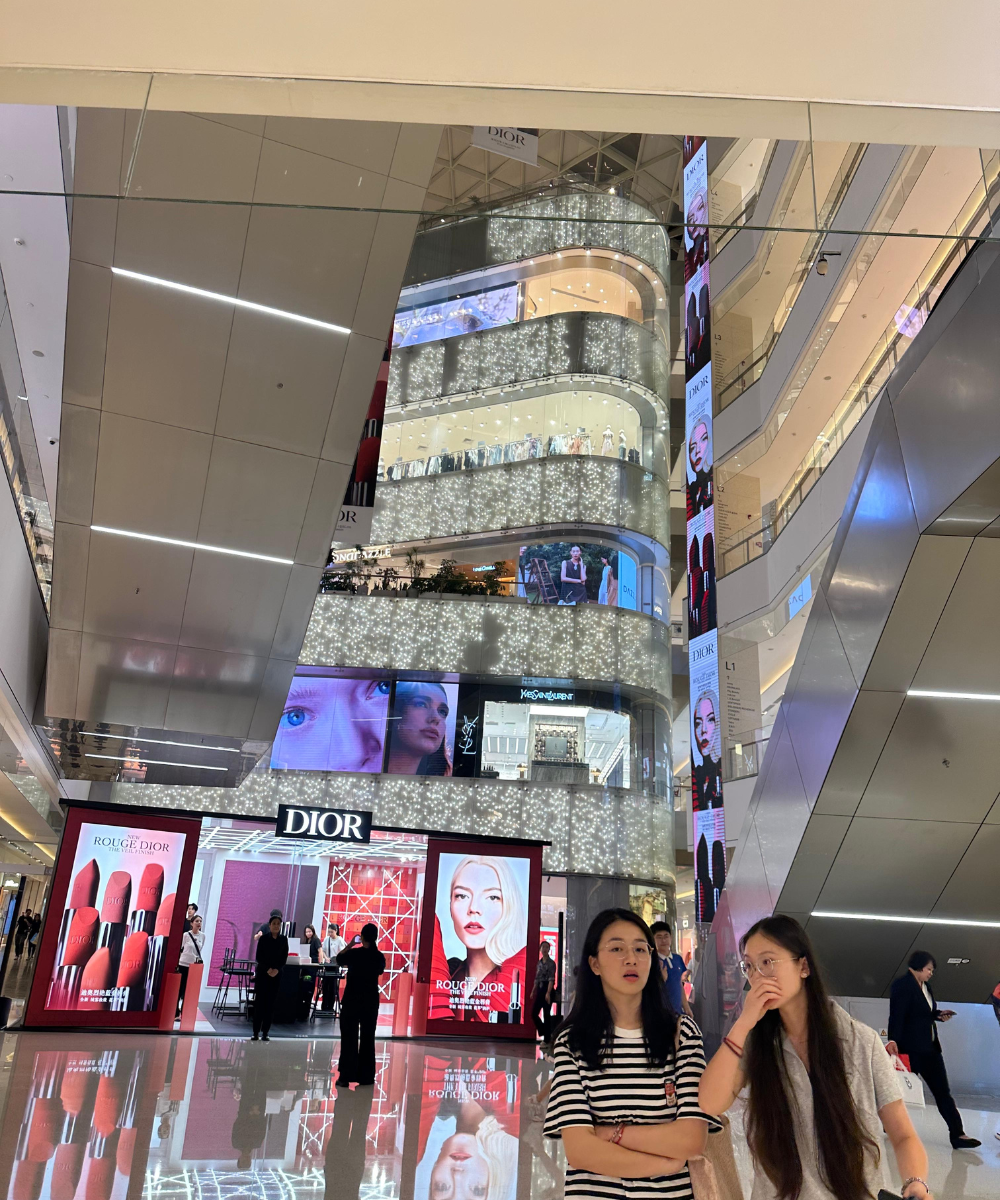Shopping iluminado com várias boutiques e pessoas passeando, destacando o ambiente moderno e vibrante típico da Ásia.
