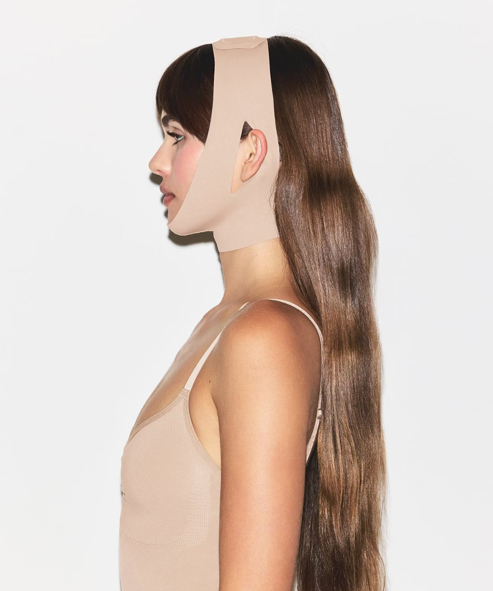 Mulher de perfil usando uma faixa compressiva no rosto, relacionada ao skincare.