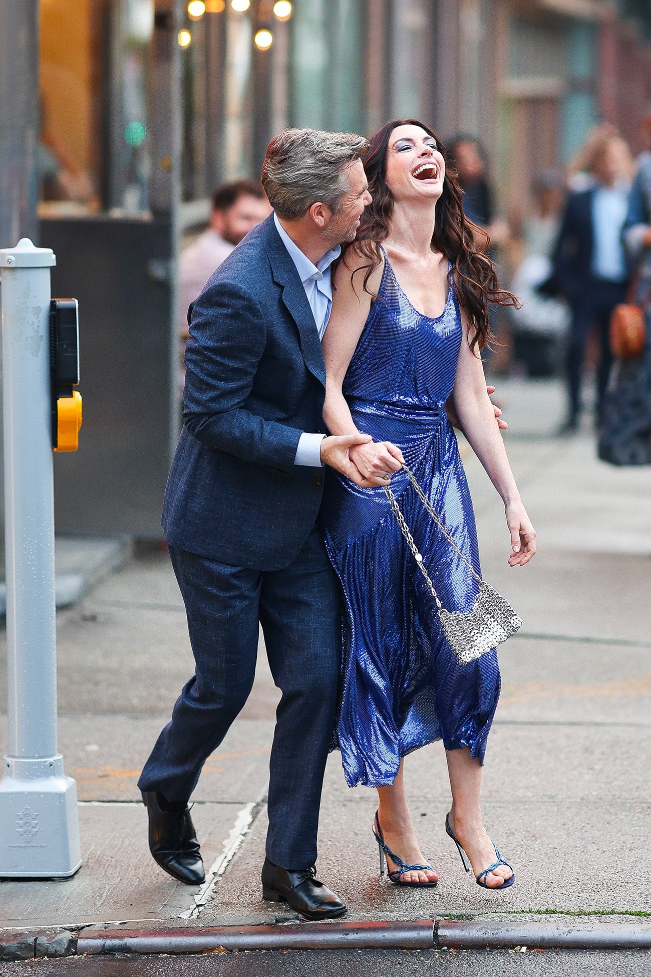 Não sei quem são as pessoas na imagem, mas elas estão rindo e caminhando juntas em uma rua. O Diabo Veste Prada 2.