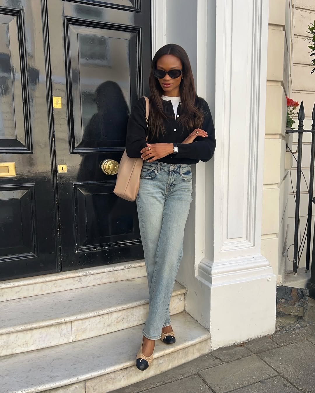 Pessoa usando jeans claros, blusa preta e sapatos elegantes, mostrando estilo casual para o trabalho.