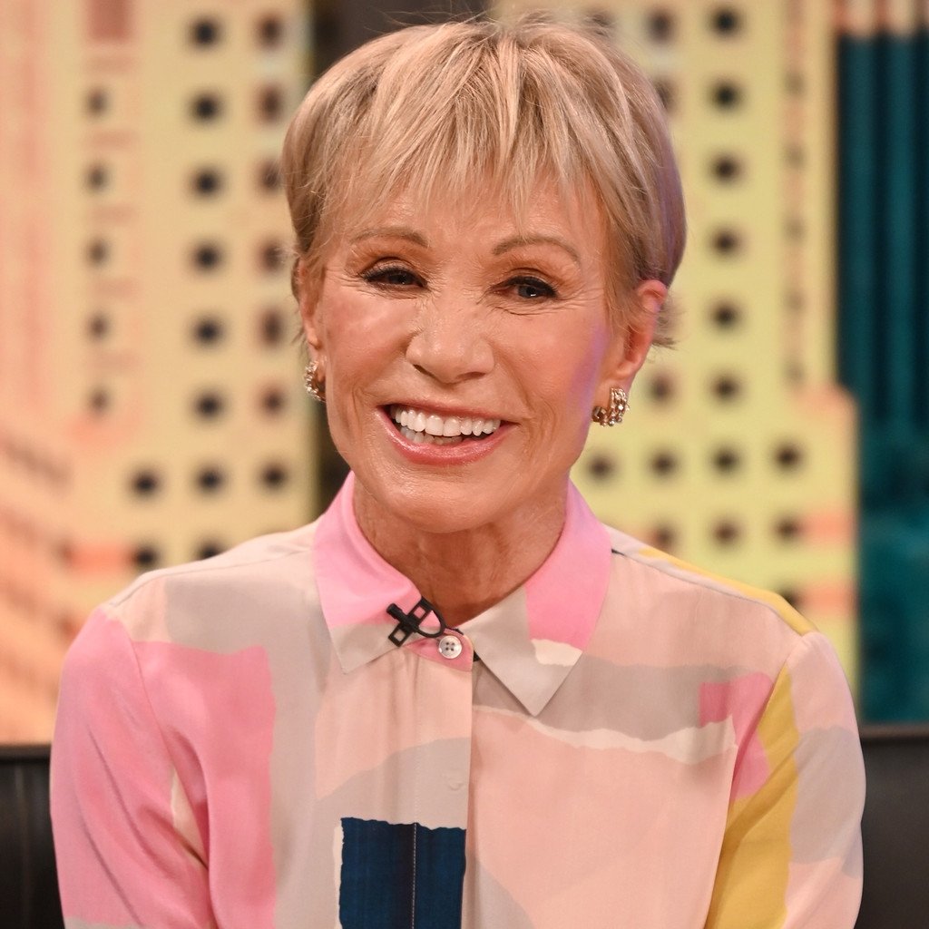 Pessoas idosas sorrindo em um programa de TV com cabelo curto e loiro.