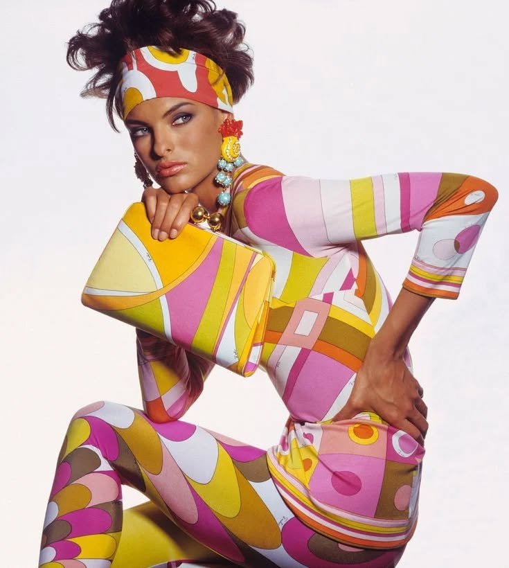 Modelo com estampa colorida vibrante, adequada para o tema pucci girl summer. Ela segura uma bolsa combinando.