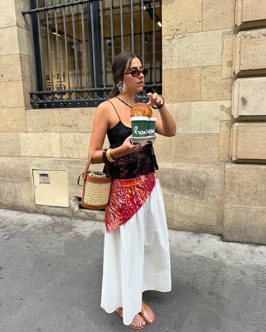 Pessoa com looks estilosos de calor, usando saia, segurando café e croissant.