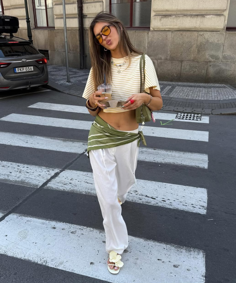 Pessoa com roupas leves atravessando a rua em dia ensolarado, em clima de verão europeu 2026.