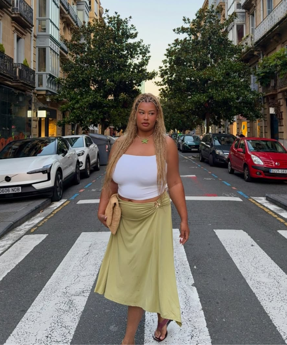 Mulher atravessando rua europeia cercada por carros e edifícios históricos, possivelmente em um dia de verão europeu 2026.