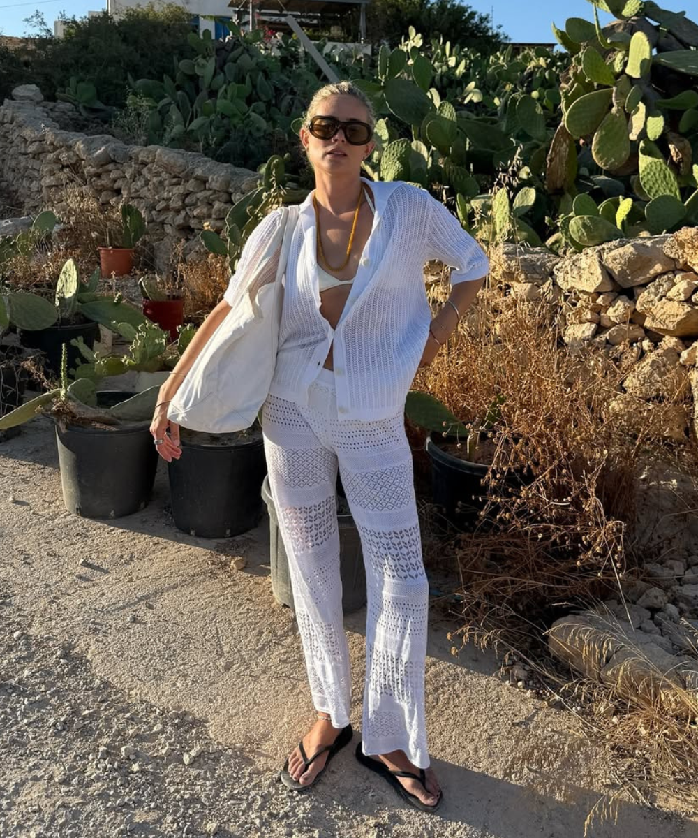 Pessoa vestida de branco com óculos de sol e bolsa em cenário de verão europeu 2026, cercada por cactos.