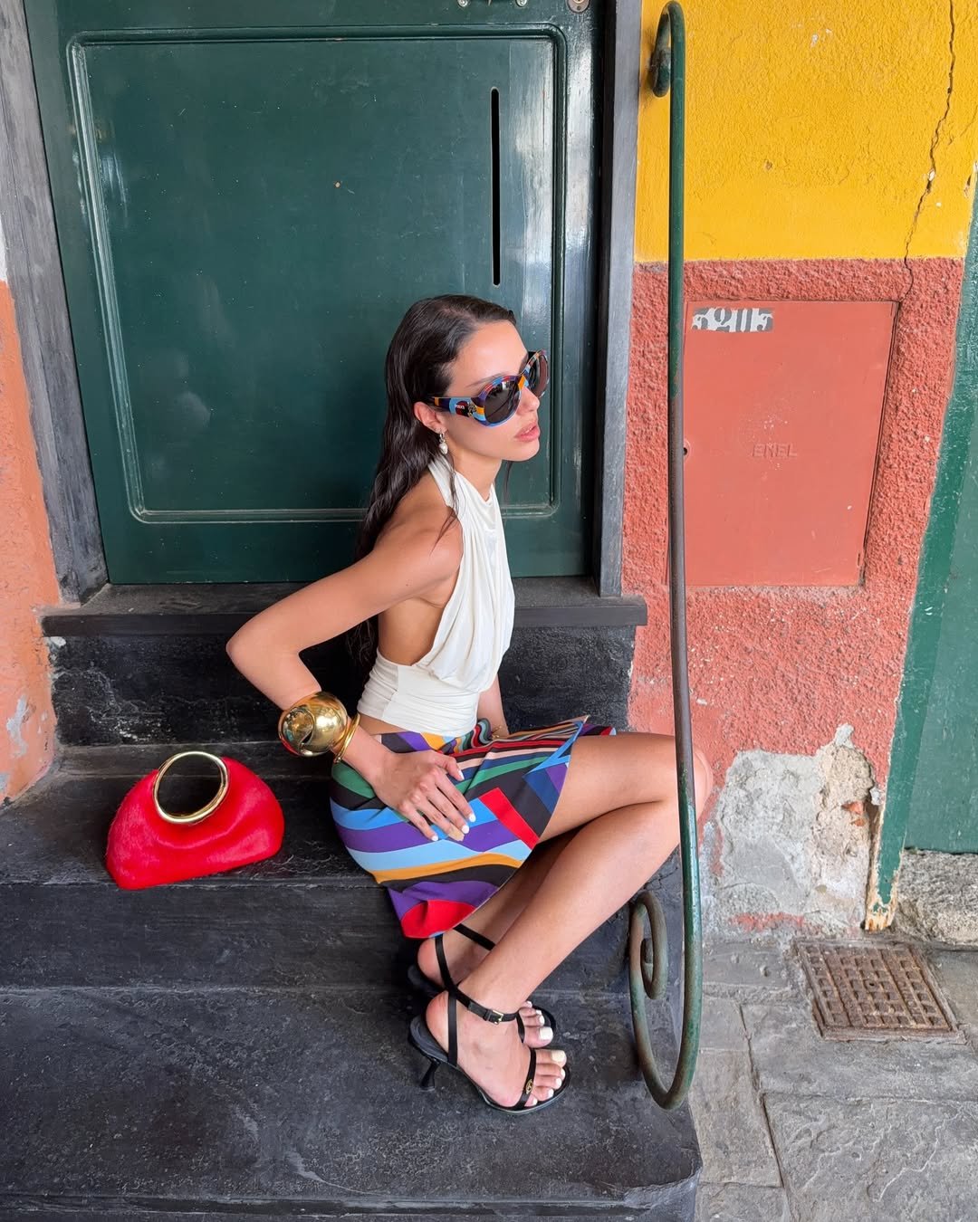 Mulher com vestuário colorido em ambiente urbano, evocando maximalismo italiano.