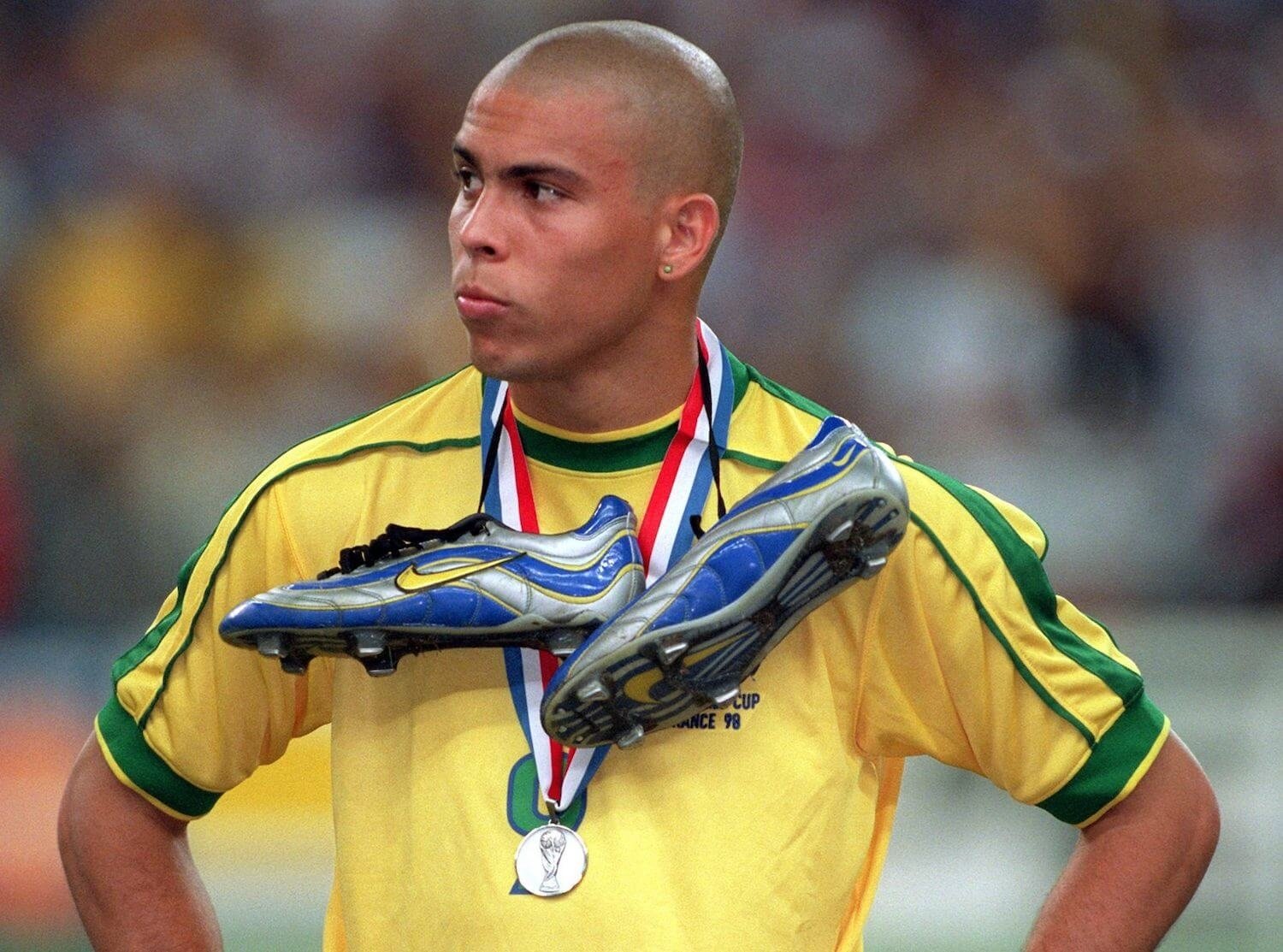 Jovem jogador de futebol com medalha de prata e camisa amarela durante cerimônia de premiação.