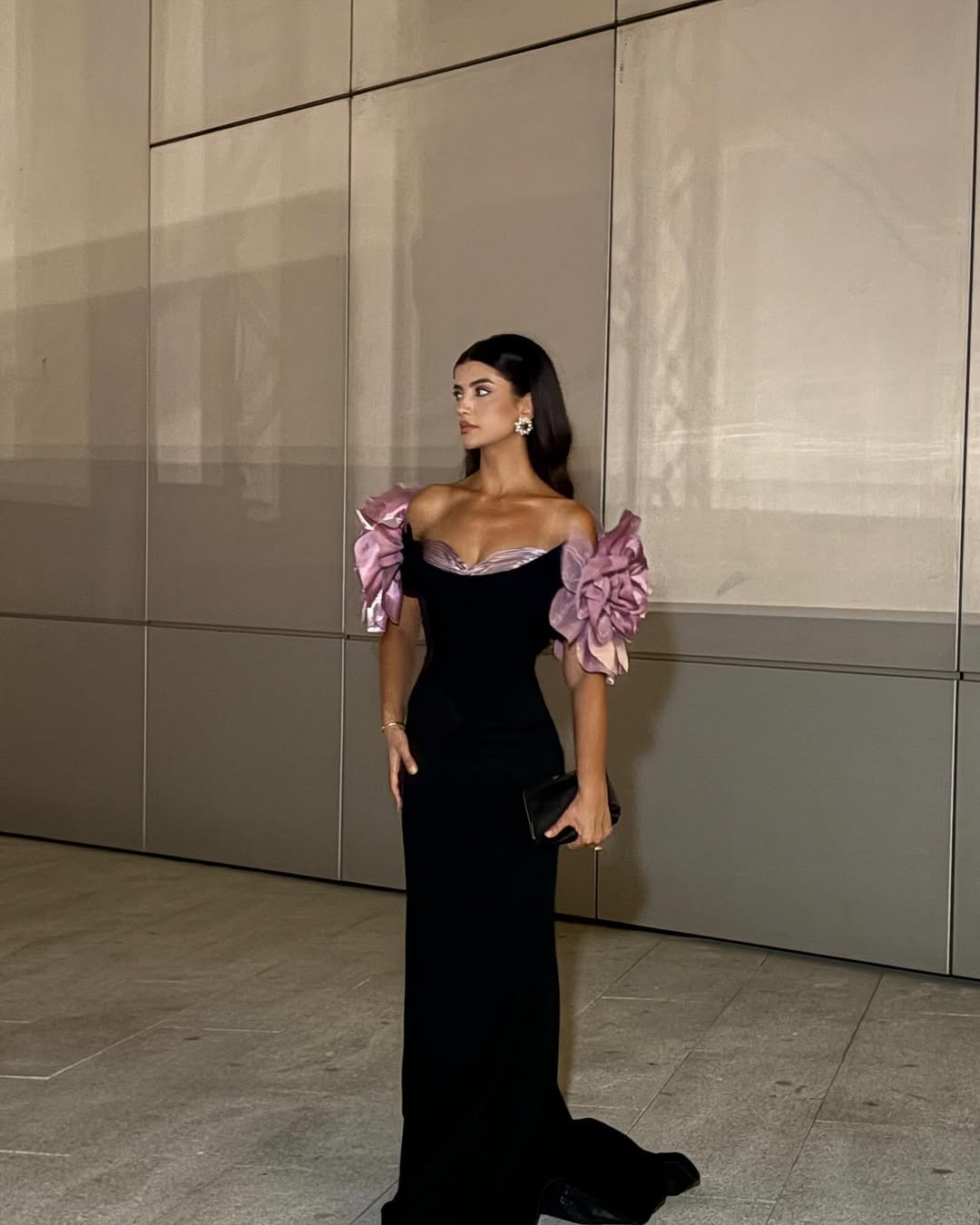 Ela usa vestido preto elegante com mangas volumosas roxas, usando melhores perfumes árabes femininos.