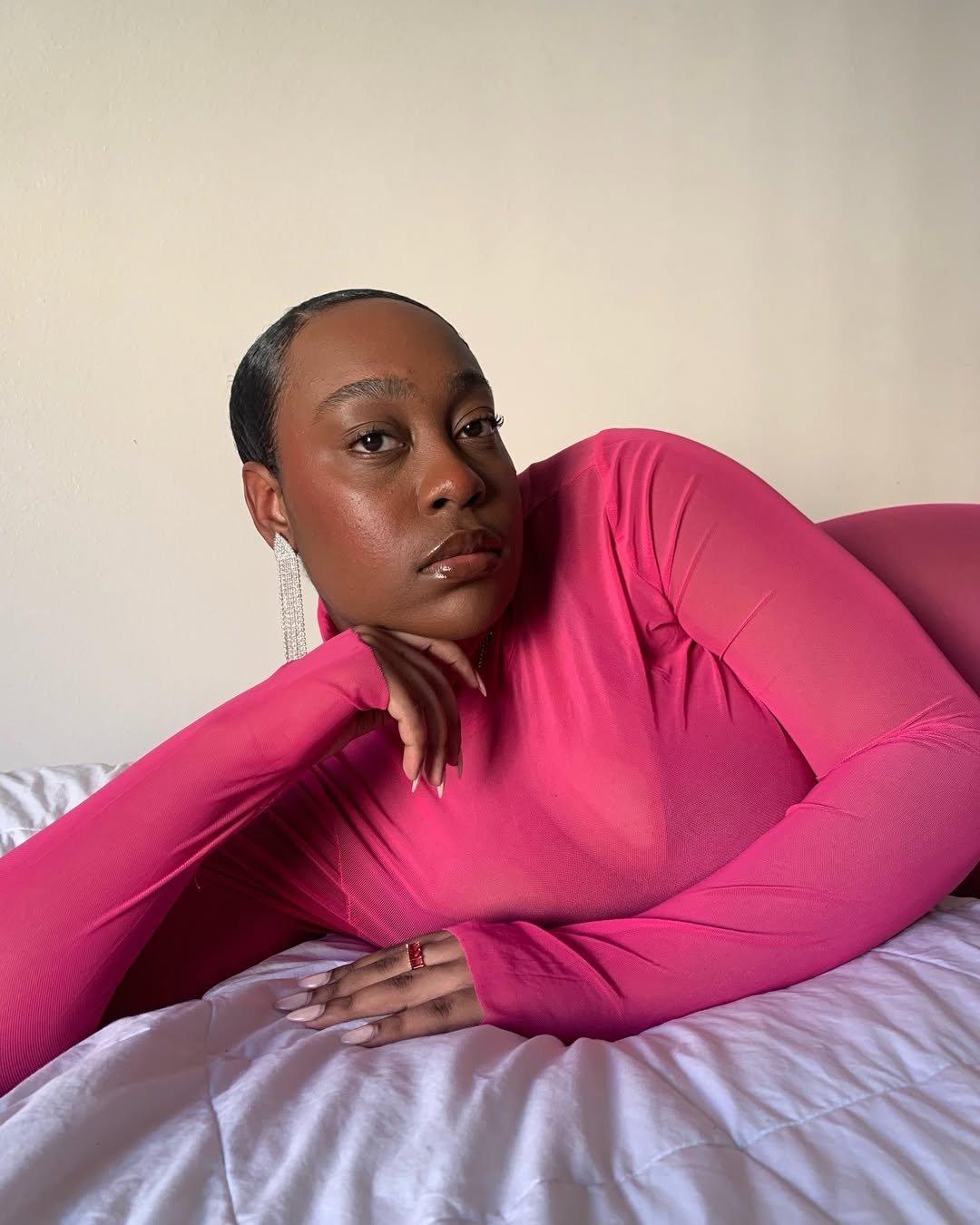 Pessoa deitada em um sofá, vestindo blusa rosa vibrante. Olhos fixos, expressão de serenidade. Como prevenir rugas por estresse