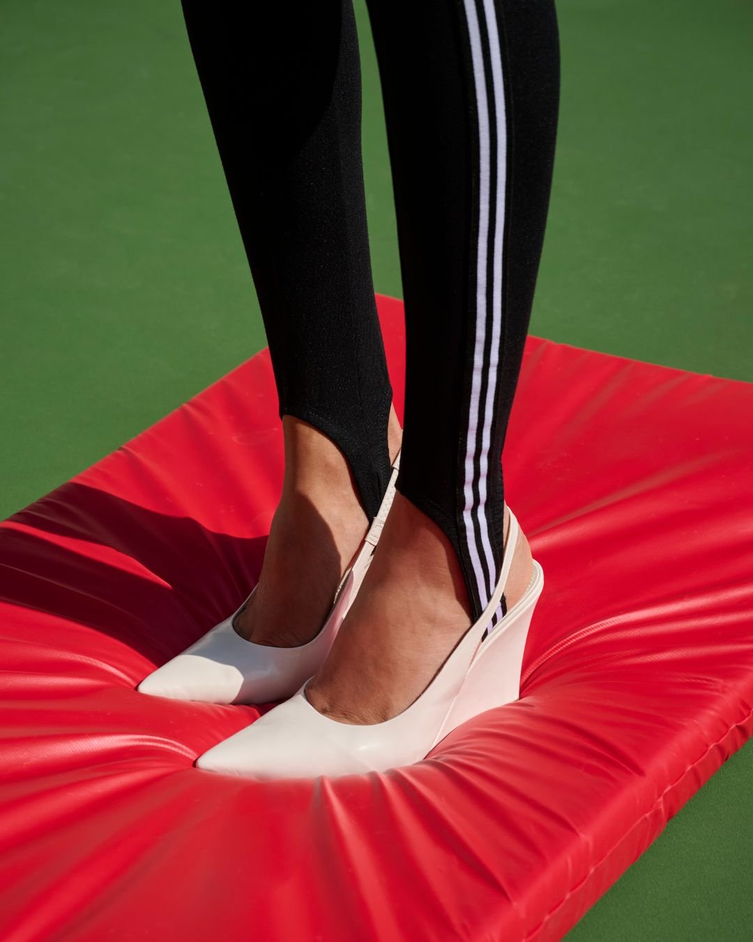 Calça justa com listras e sapatos brancos de salto sobre tapete vermelho, combinando chiqueza e conforto. mostrando como ficar chique e confortável com a nova coleção de renner
