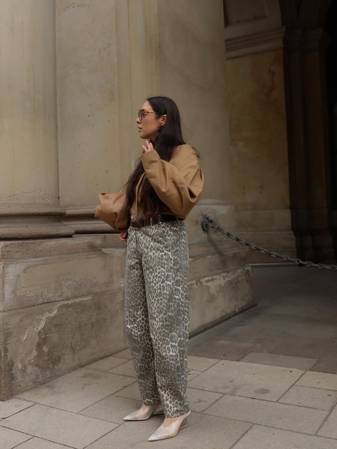 Pessoa usando blusa bege e calça estampada. Sandálias de salto da moda complementam o look elegante.