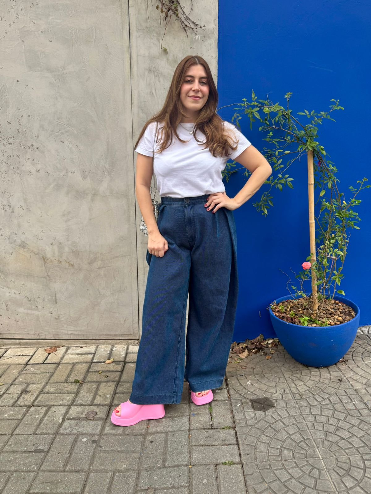 Mulher com blusa branca, calça jeans e sapatos rosa vibrante, uma das cores de sapato que vão bombar no verão de 2026