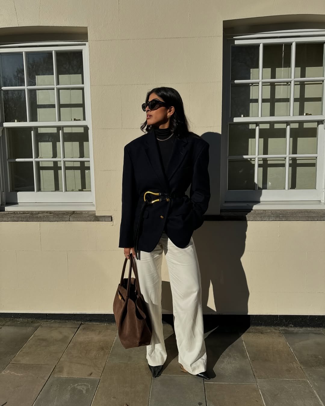 Pessoa com estilo formal, usando blazer preto e calça clara, ideal para entrevista de emprego.