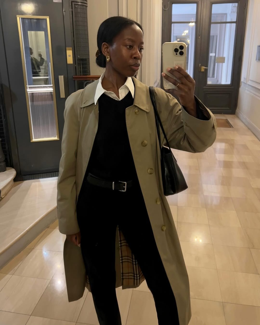 Pessoa com traje formal em corredor, segurando celular. Ideal para entrevista de emprego.