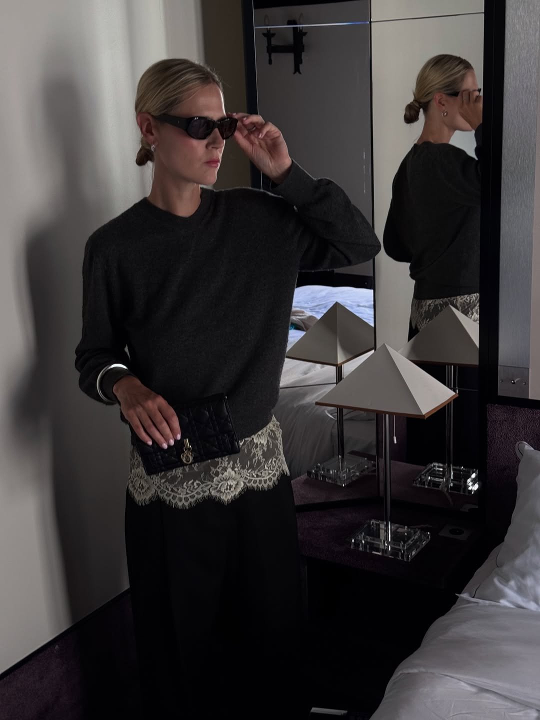 Pessoa em um quarto elegante usando óculos escuros, refletida no espelho.