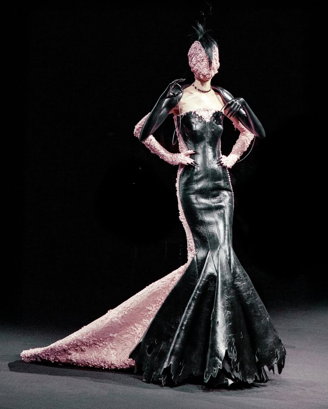 Vestido avant-garde com detalhes em preto e rosa, inspirado por Schiaparelli, apresentando texturas únicas e máscara combinando.