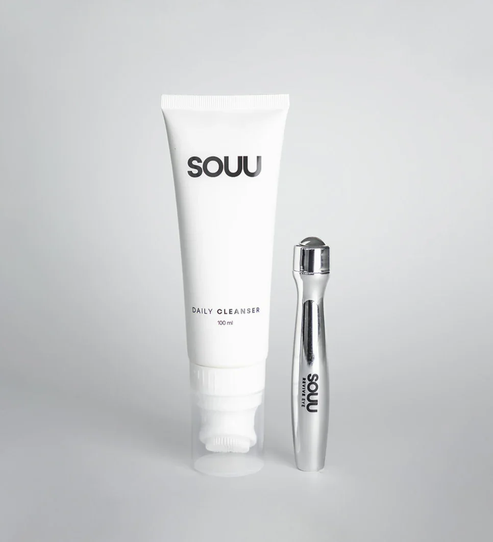 Produto de limpeza facial SOUU Beauty ao lado de massageador facial prateado.