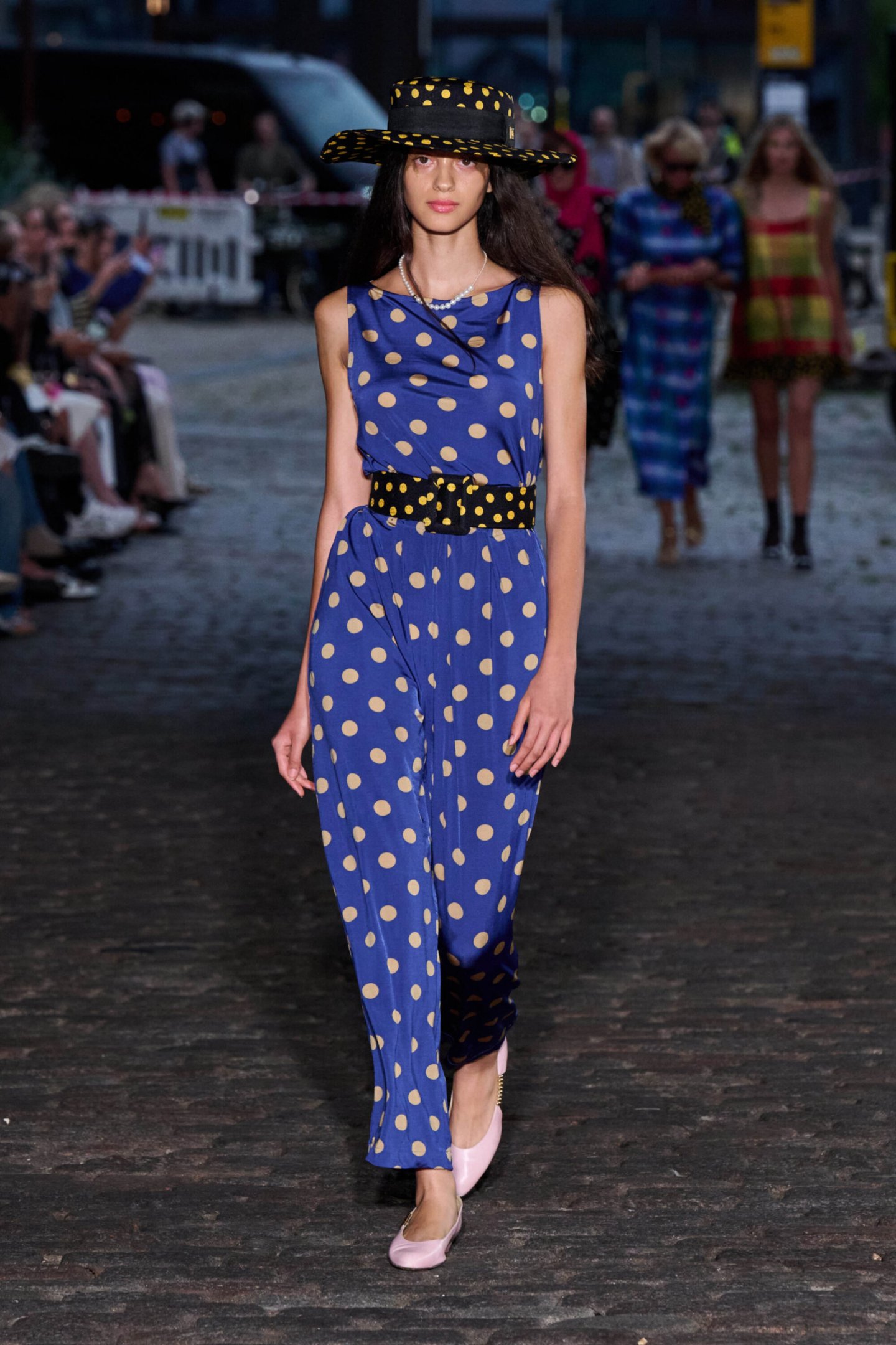Modelo desfila usando vestido azul de bolinhas amarelas e chapéu combinando na Copenhagen Fashion Week Primavera 2026.